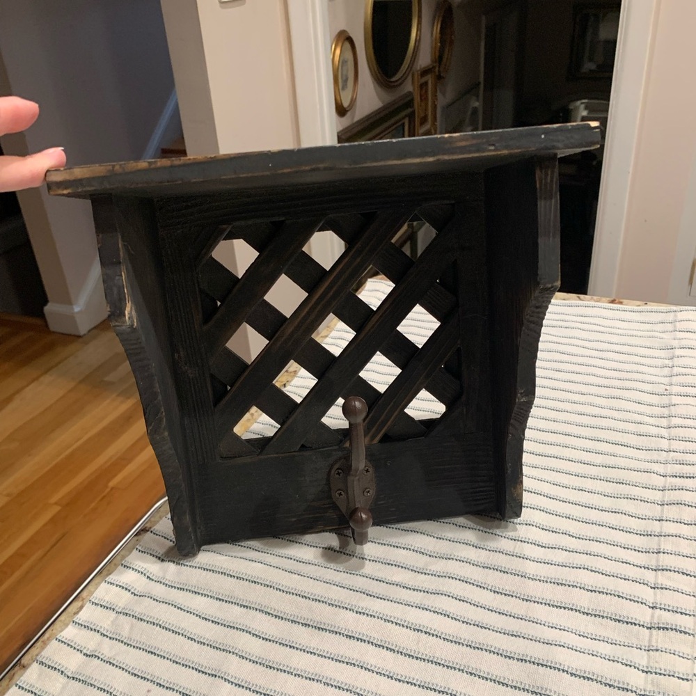 Distressed black wooden shelf with a lattice back and  hook.